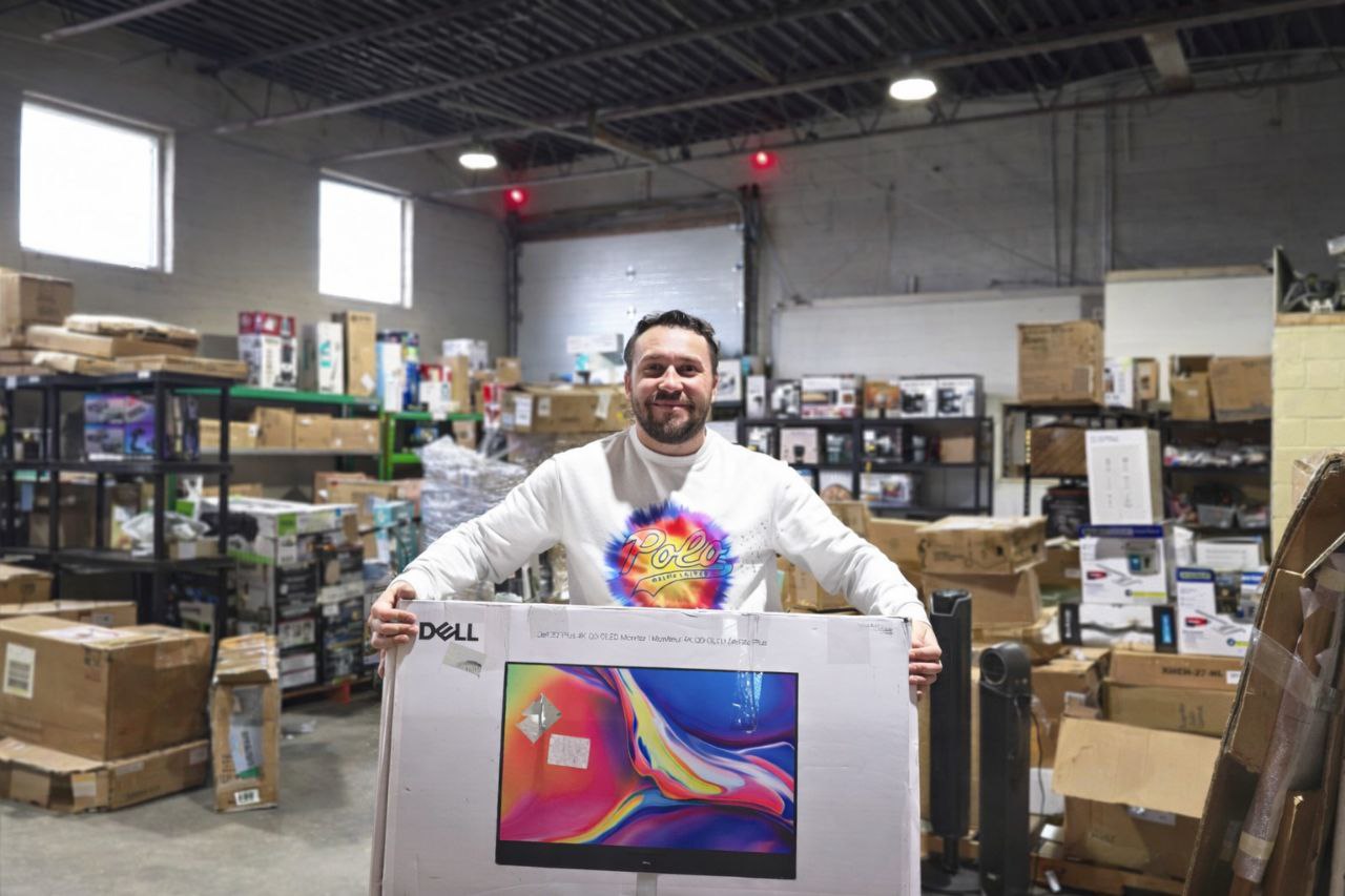 Toronto liquidation store owner holding Dell monitor in warehouse